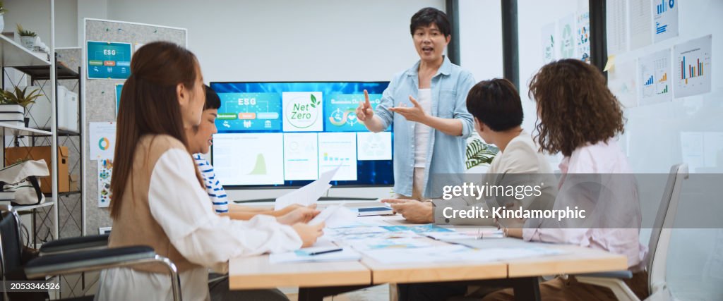 Asian business people team brainstorm meeting in green corporate office. Presentation ESG project planning. Environmental conservation, responsible business, sustainable development goal concept