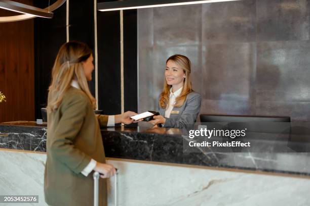 mujer que realiza un pago a través de la tecnología nfc - recepcionista fotografías e imágenes de stock