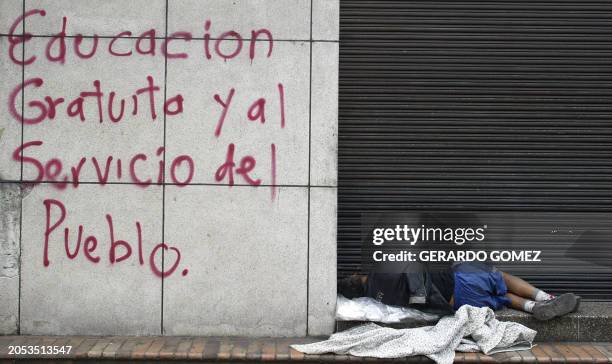 Un indigente duerme junto a un graffiti durante el Paro Nacional de Maestros en las calles de Medellin, departamento de Antioquia, Colombia el 30 de...