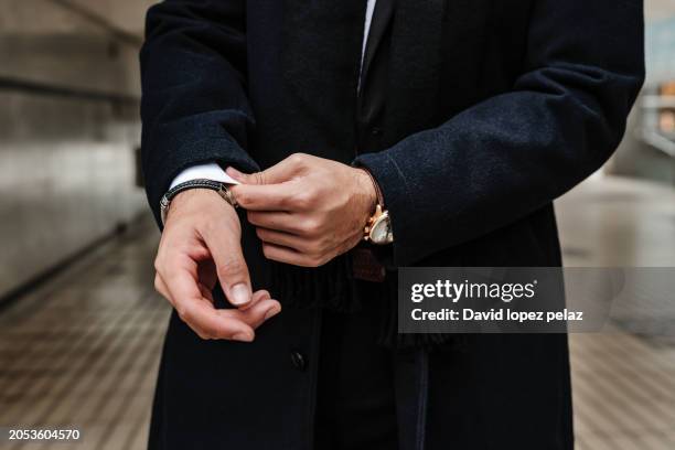 close-up of man's hands adjusting jacket sleeves in a modern urban setting. - luxusuhr stock-fotos und bilder