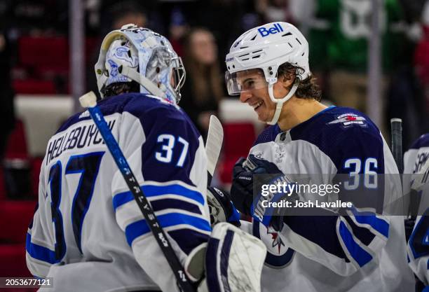 Connor Hellebuyck of the Winnipeg Jets celebrates with Morgan Barron after a 5-3 victory against the Carolina Hurricanes at PNC Arena on March 02,...