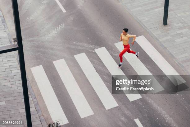 athletic man in red running tights crossing street at zebra crossing - sport determination stock pictures, royalty-free photos & images