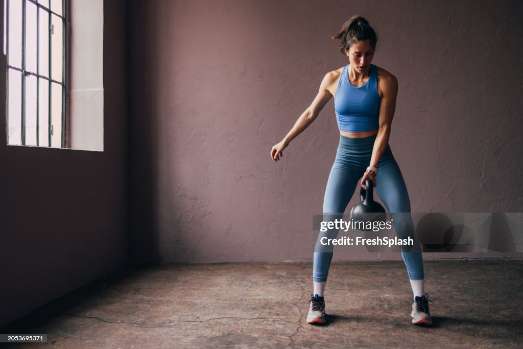 Femme concentrée faisant de l’exercice avec un kettlebell dans un gymnase