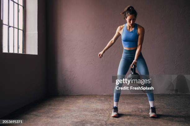 focused woman exercising with kettlebell in a gym setting - fitness center wall stock pictures, royalty-free photos & images