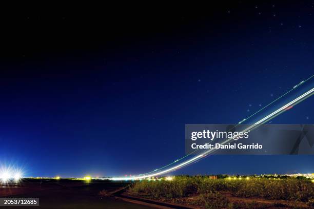 airplane trails in long exposure while night takeoff, light trails while night takeoff in action. - landing light stock pictures, royalty-free photos & images