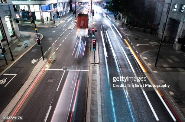 fast moving traffic at night on a busy city street with light trails. - vehicle light stock pictures, royalty-free photos & images