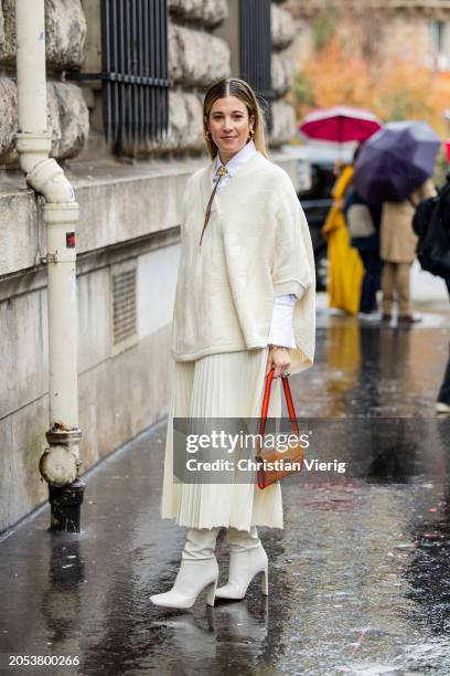 Guest wears creme white pleated skirt, knit, orange bag, white button shirt outside Hermes during the Womenswear Fall/Winter 2024/2025 as part of...