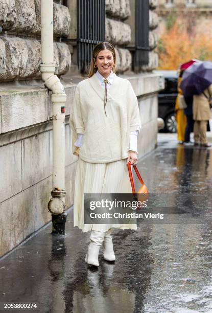 Guest wears creme white pleated skirt, knit, orange bag, white button shirt outside Hermes during the Womenswear Fall/Winter 2024/2025 as part of...