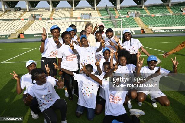Queen Mathilde of Belgium poses with young athletes during a meeting with Ivorian athletes, at the Laurent Poku Stadium in San Pedro, during a royal...