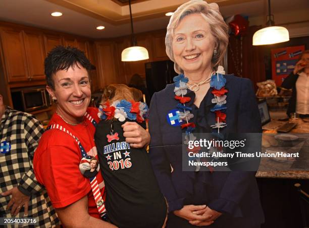 Kimberly Powell holds her partner's dog Nayla who is wearing an election t-shirt as she stands next to a Hillary Clinton cardboard cutout at an...