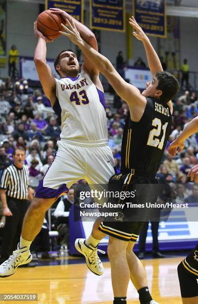 University at Albany's Greig Stire is defended by UMBC's Sam Schwietz as he goes up for a shot during a basketball game at the SEFCU Arena on...