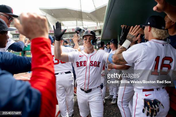 Tyler O'Neill of the Boston Red Sox reacts with teammates in the dugout after hitting a home run during the third inning of a Grapefruit League...