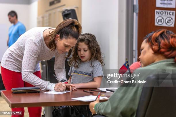 Young girl observes and participates as her guardian shows her the voting process on Super Tuesday at WTVI/PBS studios, Precinct 46 in Mecklenburg...