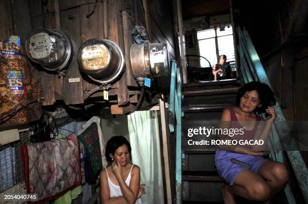 Housewife Perla Soteo and a neighbor sit in front of their shanty house with an electric meter in Manila on June 4, 2008. President Gloria Arroyo...