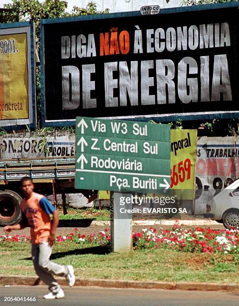 Man crosses a street in front of a placard reading "Say no to the Power Economy," in Brasilia, Brazil, 21 May 2001, as Brazilian President Fernando...