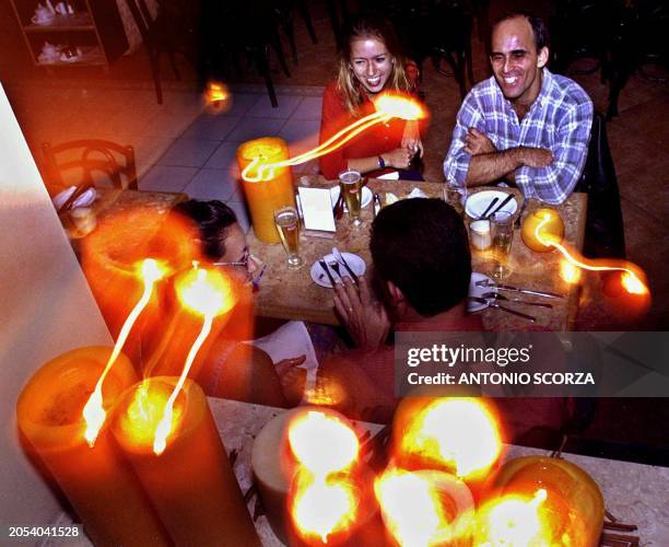 Clients at a restuarant, illuminated by candelight, 5 June 2001, in Rio de Janeiro, Brazil. Clientes de un restaurante cenan, iluminados por velas,...