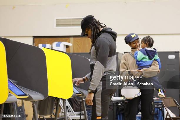 Boyle Heights, CA Tiffany Ellerby, right, holds Braxton Ellerby while her husband Brandon Ellerby, of Los Angeles, votes while they take turns...