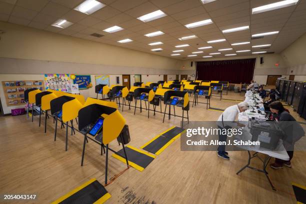 Boyle Heights, CA Sister Reina Perea, right, of Boyle Heights, drops off her ballot to poll workers amid an empty room as voters cast their ballots...