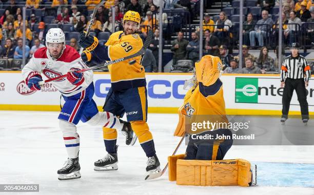 Alex Newhook of the Montreal Canadiens battles in front of the net against Roman Josi and Juuse Saros of the Nashville Predators during an NHL game...