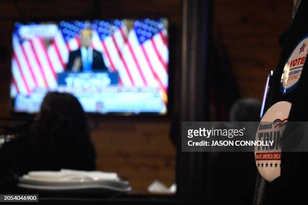 Supporter of former US president and Republican presidential candidate Donald Trump wears campaign badges during a Super Tuesday watch party at Wide...