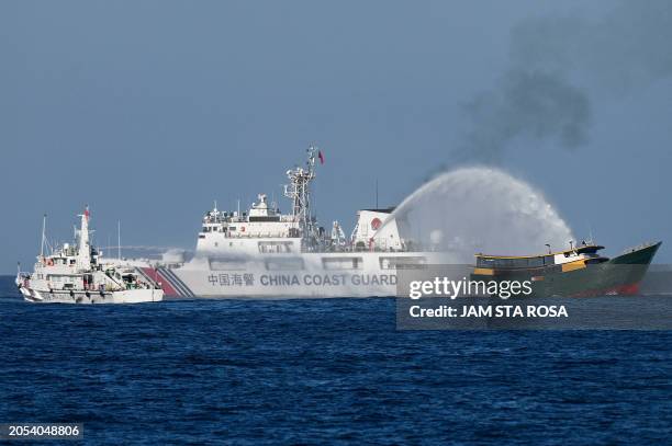 This photo taken on March 5, 2024 shows China Coast Guard vessels deploying water cannons at the Philippine military chartered Unaizah May 4 during...