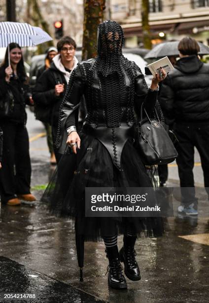 Guest is seen wearing a black leather and tule outfit, black back, black shoes and black net headpiece outside the Hermes show during the Womenswear...