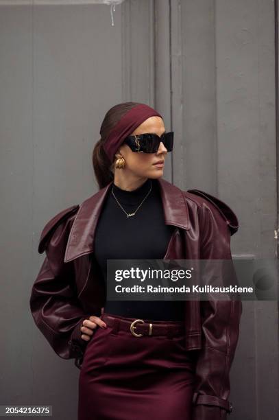 Nina Sandbech wears burgundy headband, burgundy leather jacket, black top, burgundy pencil maxi skirt with a belt, YSL black sunglasses and YLS bag...