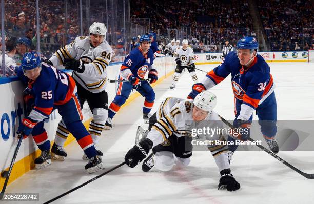 Kyle MacLean of the New York Islanders hits Trent Frederic of the Boston Bruins during the first period at UBS Arena on March 02, 2024 in Elmont, New...