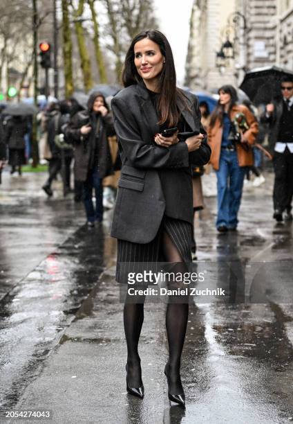 Alex Riviere is seen wearing a gray jacket, black and cream striped skirt and stockings outside the Hermes show during the Womenswear Fall/Winter...