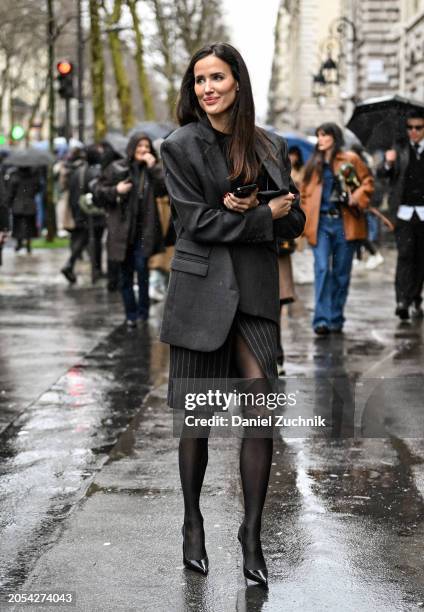 Alex Riviere is seen wearing a gray jacket, black and cream striped skirt and stockings outside the Hermes show during the Womenswear Fall/Winter...