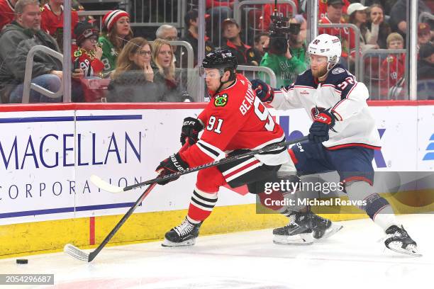 Anthony Beauvillier of the Chicago Blackhawks and Alexander Nylander of the Columbus Blue Jackets battle for control of the puck during the first...