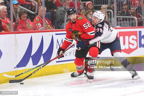 Reese Johnson of the Chicago Blackhawks and Damon Severson of the Columbus Blue Jackets battle for control of the puck during the first period at the...