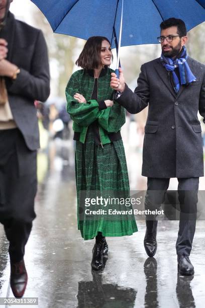 Olivia Palermo wears a green bomber jacket , a pleated midi skirt, black shiny leather boots, outside Elie Saab, during the Womenswear Fall/Winter...