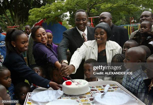 Kenyan KANU official presidential candidate, Uhuru Kenyatta, gets help to cut a Christmas cake at the SOS Childrens VIllage in Nairobi, 25 December,...