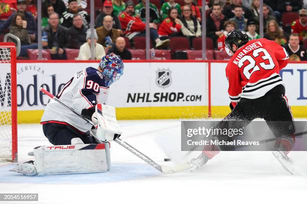 Elvis Merzlikins of the Columbus Blue Jackets makes a save against Philipp Kurashev of the Chicago Blackhawks during the third period at the United...