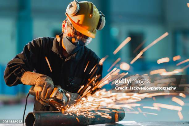 expert bricklayer using a cutter to cut an iron beam while shooting brightly coloured sparks - grinding stock pictures, royalty-free photos & images