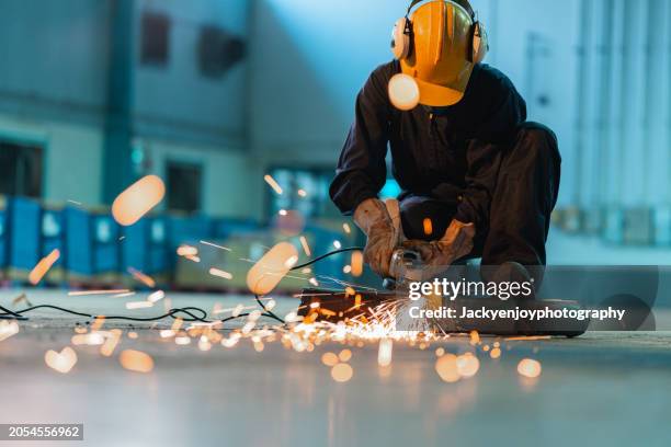a metalworker in a workshop cutting metal - moler fotografías e imágenes de stock