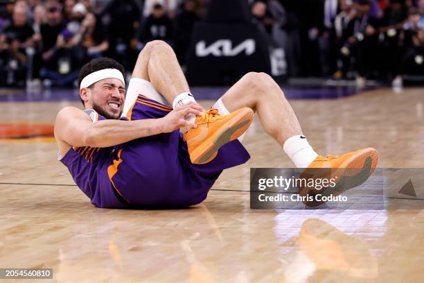 Devin Booker of the Phoenix Suns reacts after an apparent injury during the fourth quarter against the Houston Rockets at Footprint Center on March...