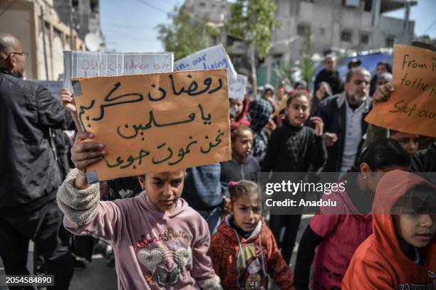 Palestinian children hold a representational funeral for their 10-year-old peer Yezen Al-Kfarna who died of malnutrition, and protest the famine...