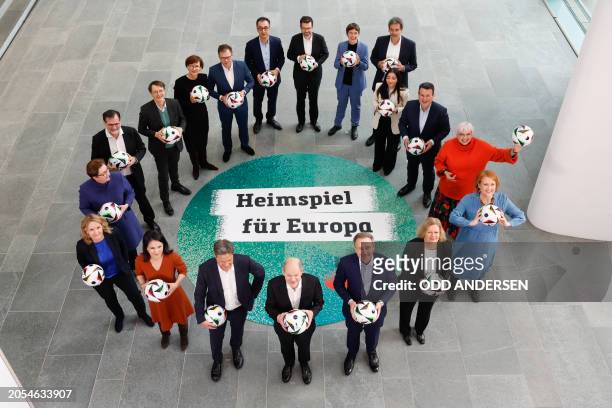 German Chancellor Olaf Scholz holds a football as he poses in a circle with German Minister of Economics and Climate Protection Robert Habeck, German...