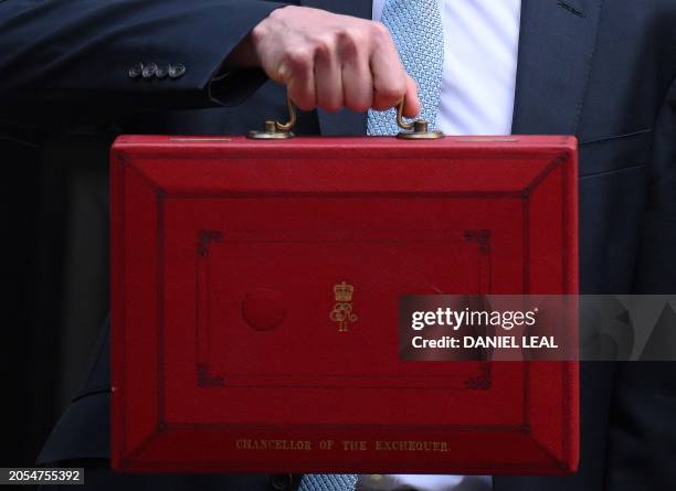 Britain's Chancellor of the Exchequer Jeremy Hunt poses with the red Budget Box as he leaves 11 Downing Street in central London on March 6 to...
