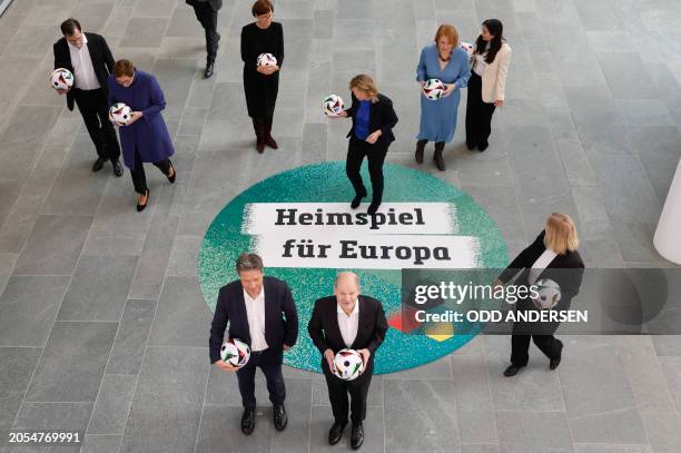 German Chancellor Olaf Scholz holds a football as he prepares to pose in a circle with with German Minister of Economics and Climate Protection...