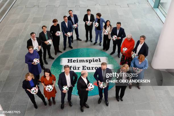 German Chancellor Olaf Scholz holds a football as he prepares to pose in a circle with German Minister of Economics and Climate Protection Robert...