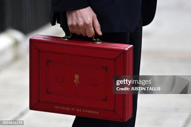 Britain's Chancellor of the Exchequer Jeremy Hunt poses with the red Budget Box as he leaves 11 Downing Street in central London on March 6 to...