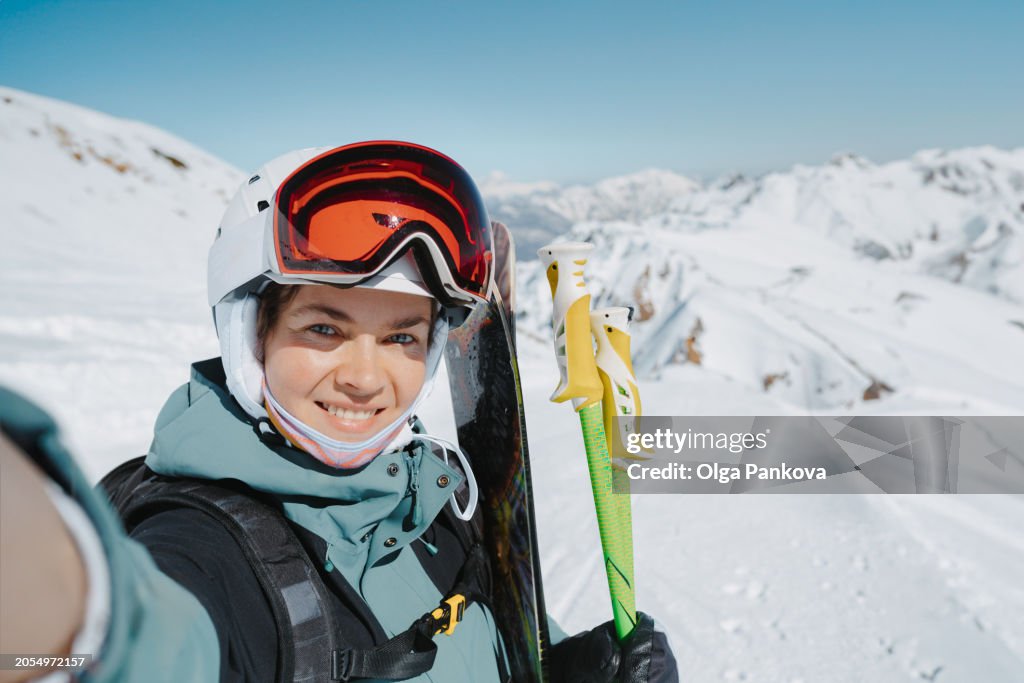 Middle-aged woman takes a self-portrait, selfie while alpine skiing in the mountains.