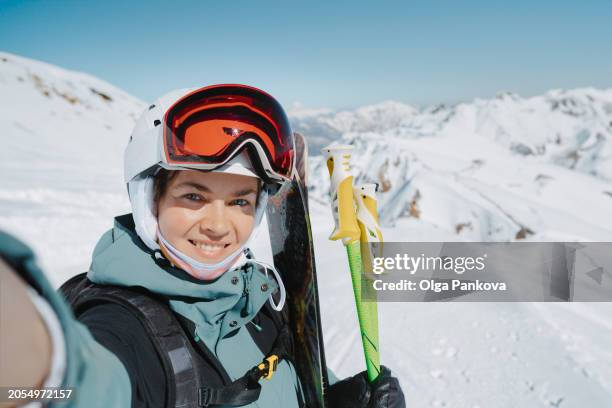 middle-aged woman takes a self-portrait, selfie while alpine skiing in the mountains. - skier portrait stock pictures, royalty-free photos & images