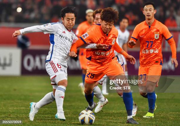 Yokohama's Kouta Watanabe fights for the ball with Shandong Taishan's Gao Zhunyi during the AFC Champions League quarterfinal match between Japan's...