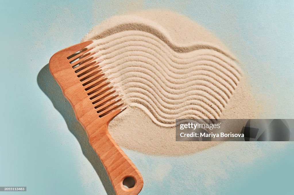 Wooden comb on the sand with marks.