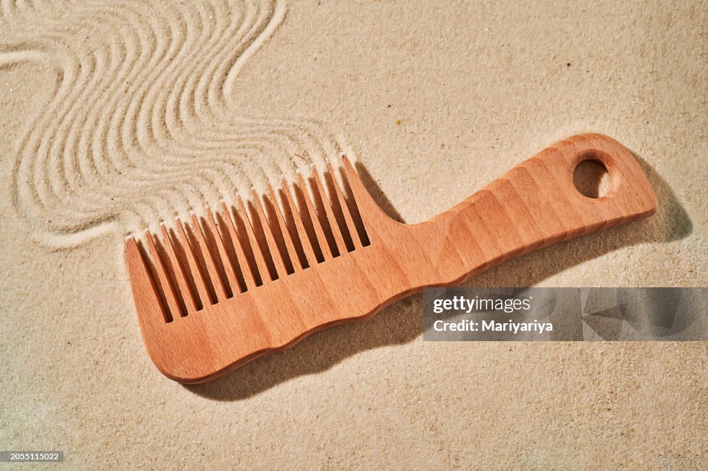 Wooden comb on the sand with marks.