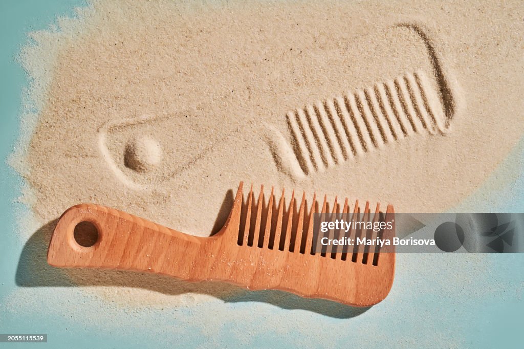 Wooden comb on the sand with marks.